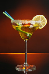 Yellow cocktail in glass on color background