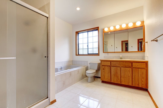 Large white bathroom with tub, shower and wood cabinet.