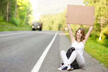 Beautiful young female hitchhiker with cardboard
