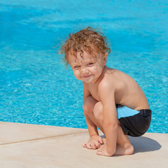 happy little boy sitting near the pool