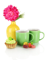 Cups of tea with candy,cake and flower isolated on white