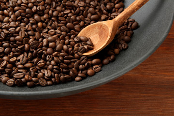 Black wok pan with coffee beans on wooden table, close up