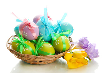 Bright easter eggs with bows in basket, isolated on white