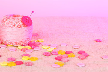 Beautiful buttons and a ball of yarn on a pink background