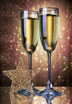 Two glasses of champagne on bright background with lights