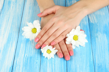 Woman hands with pink manicure and flowers, on color background