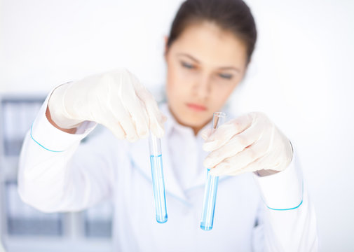Young chemical female researcher holding two glass tubes