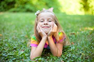 Beautiful little girl is lying on the green grass