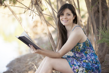 Cute young woman reading a book while relaxing outdoors