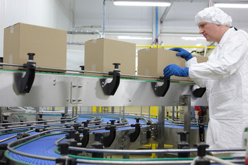 caucasian man worker in white apron  at packing line in factory