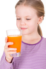 Young, smiling child looking and drinking orange juice