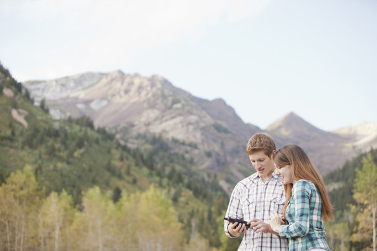 Caucasian couple looking at GPS device in remote area