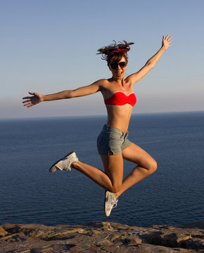 Happy  girl jumping on coast