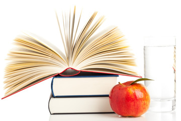 Books with apple and glass of water