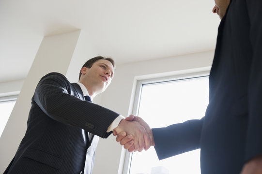 Businessmen shaking hands in office