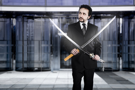 Businessman with two Japanese swords at the entrance of an offic