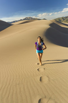 Hispanic woman running on sand dune