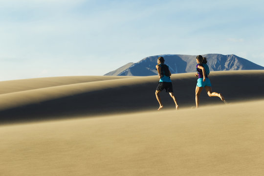 Hispanic couple running on sand dune