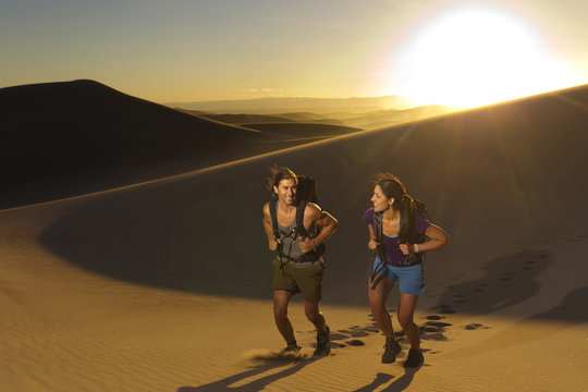 Hispanic couple walking up sand dune