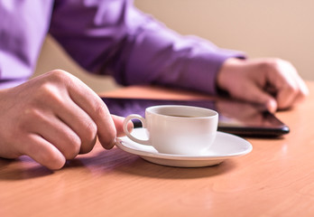 A man holding a cup of coffee and working on a Tablet PC