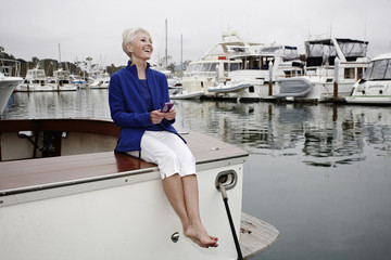Woman sitting on boat text messaging on cell phone