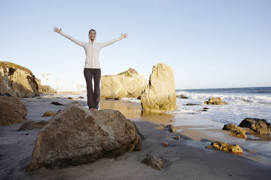 Hispanic woman on beach with arms outstretched