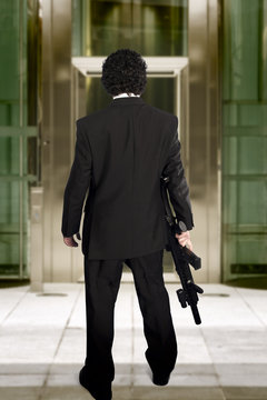 man entering a business building with a machine gun