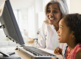 African American grandmother and granddaughter using computer together