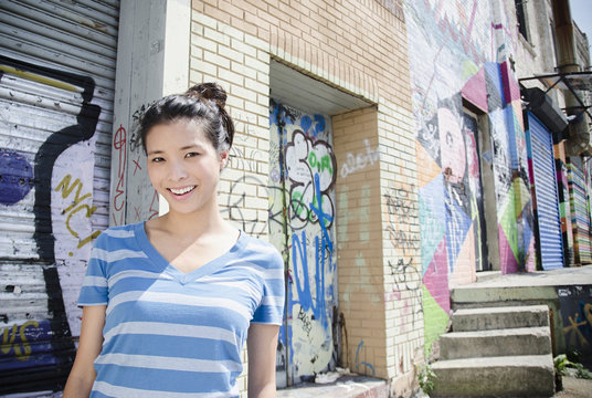 Asian woman near urban graffiti