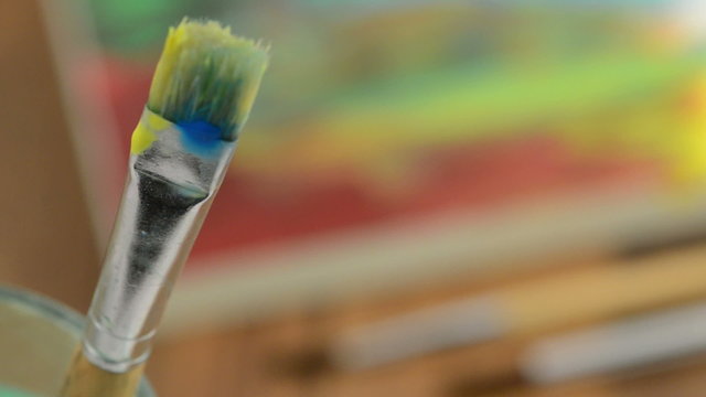 Rack focus paintbrush in glass to paper with painting