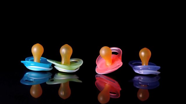 Baby pacifier falling beside three others