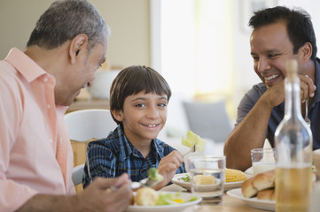 Hispanic grandfather, father and son eating dinner