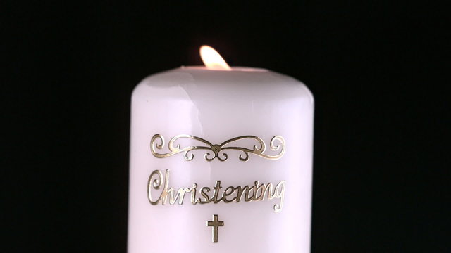 Lit christening candle flickering