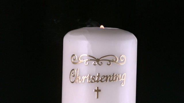 Lit christening candle flickering and going out