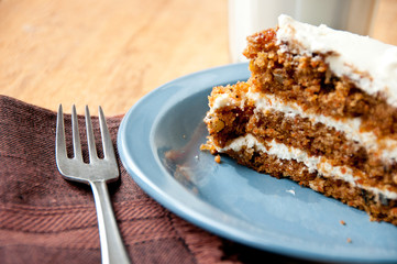 Carrot cake on a blue plate with milk and fork