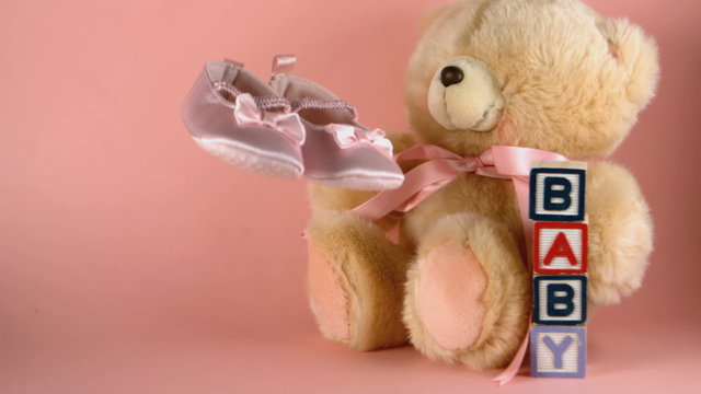Baby shoes falling next to a teddy bear and baby blocks
