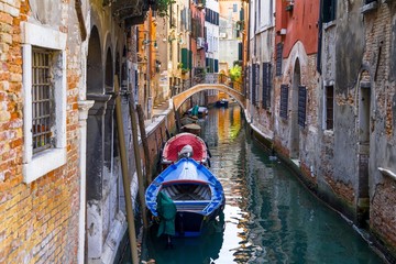 Small channel in Venice, Italy with boats parked around