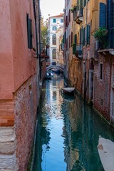 Fototapeta na wymiar Ciemny i samotny kanał w Wenecji z zaparkowanych w okolicy łodzi