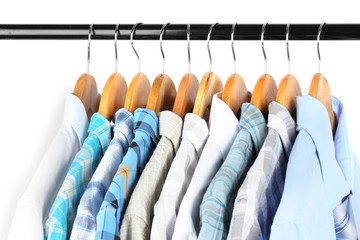 Shirts with ties on wooden hangers on light background