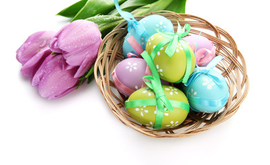 Bright easter eggs in basket and tulips, isolated on white