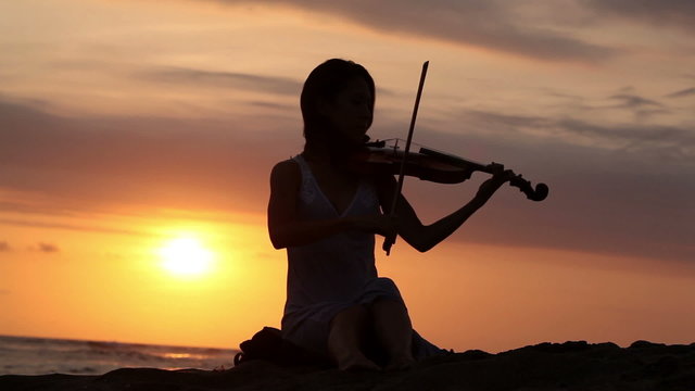 Violinist playing on violin romantic music while sunset