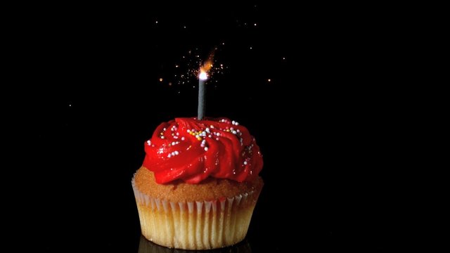 Sparkler burning on red birthday cupcake