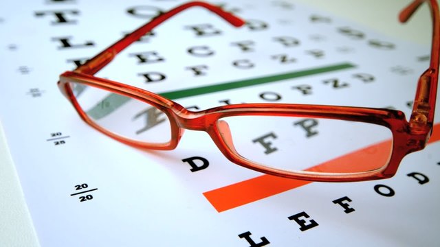 Red reading glasses falling onto eye test