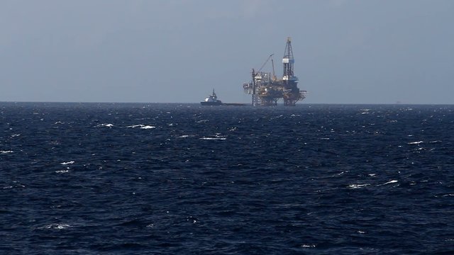 Jack up drilling rig and crew boat in the middle of the coean