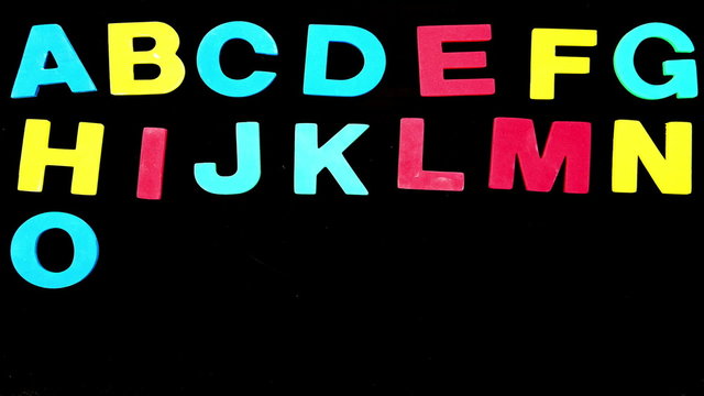 Colourful alphabet appearing on black background