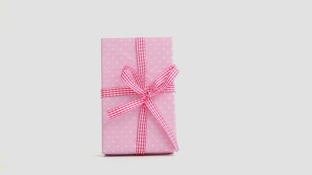 Hand putting down pink gift and then taking it away