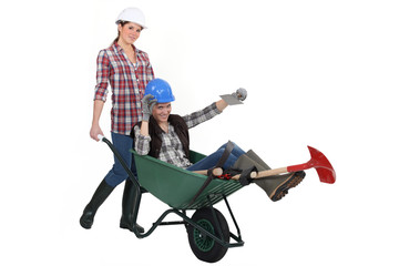 Two women messing around wuth wheelbarrow