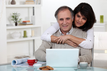 A middle age couple looking at a laptop.