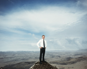 Businessman on a rock in the mountains