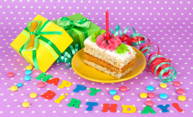 Colorful birthday cake with candle and gifts on pink background